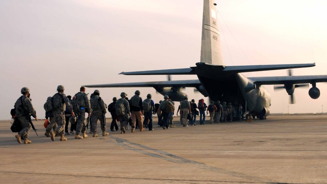 Repliegue logístico de tropas y equipo militar estadounidense desde una base en Irak, no un combate — carga de vehículos/material en una pista o instalación aeroportuaria