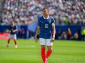 Futbolista de selección nacional en acción de juego nocturno, evocando el partido en el que ocurrió la lesión, sin representar la lesión misma ni una escena médica no documentada