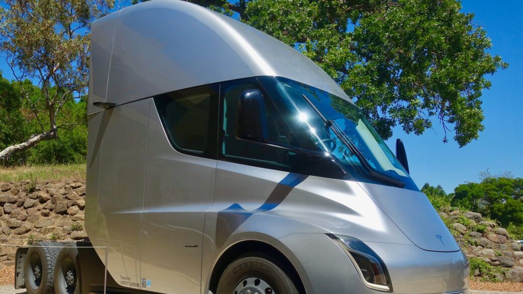 Un camión eléctrico tipo Tesla Semi ya entregado, en un patio de logística o planta industrial, que comunique 'camión eléctrico de carga en operación real' más que 'concepto o prototipo'.
