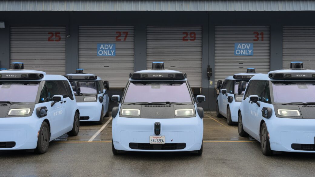 Vehículo autónomo tipo robotaxi circulando de noche por una avenida urbana, con sensor de techo visible