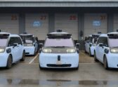 Vehículo autónomo tipo robotaxi circulando de noche por una avenida urbana, con sensor de techo visible