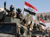 Celebración nocturna callejera en Irak por el feriado del Día de la Soberanía, con banderas iraquíes y ambiente festivo, no una escena militar