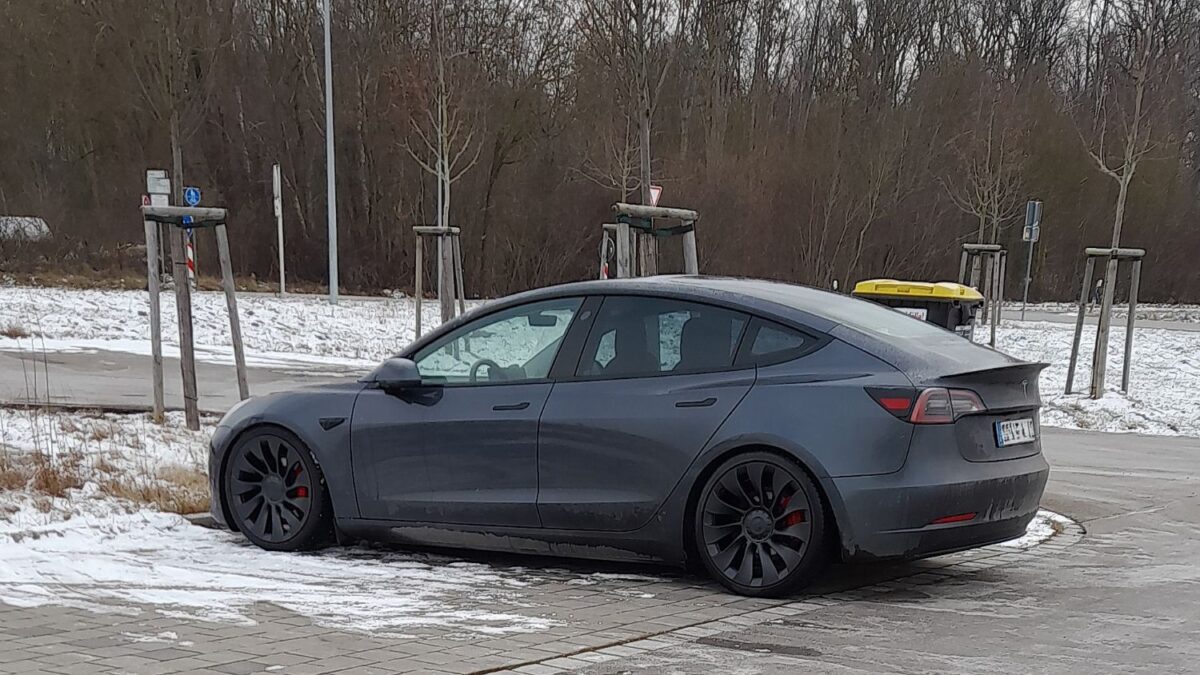Un vehículo Tesla circulando en una calle de una ciudad europea con rasgos holandeses (ciclovías, arquitectura típica), evocando el contexto de la aprobación regulatoria del sistema de conducción asistida sin representar el hecho no fotografiable (la disputa por correos y la revisión regulatoria).