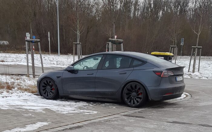 Un vehículo Tesla circulando en una calle de una ciudad europea con rasgos holandeses (ciclovías, arquitectura típica), evocando el contexto de la aprobación regulatoria del sistema de conducción asistida sin representar el hecho no fotografiable (la disputa por correos y la revisión regulatoria).